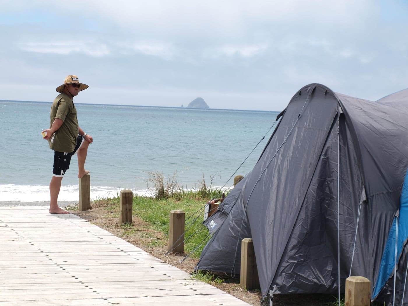 A large tent beside a beach access boardwalk and a camper looking toward the sea at Port Jackson.