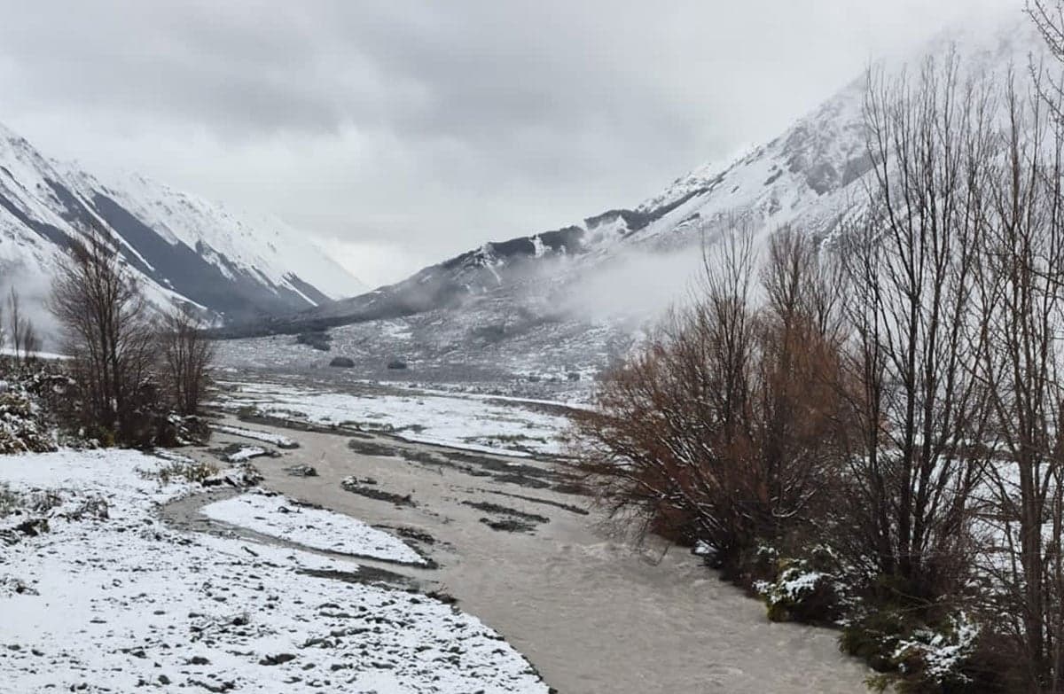 An icy snow-covered mountain landscape with a small river running through.
