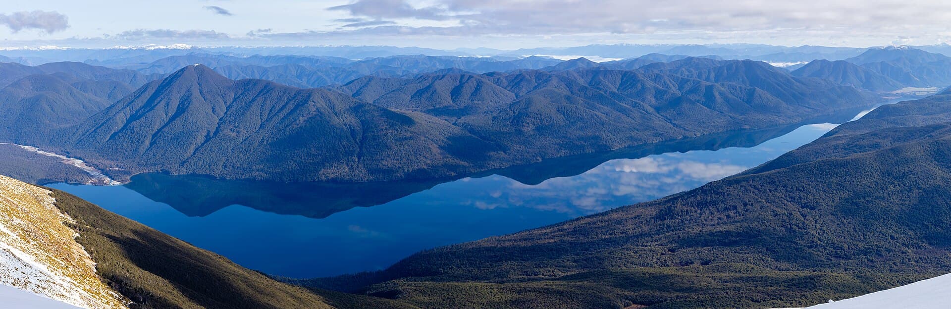 Wide elevated view of Lake Rotoroa surrounded by forested mountains in Nelson Lakes National Park.