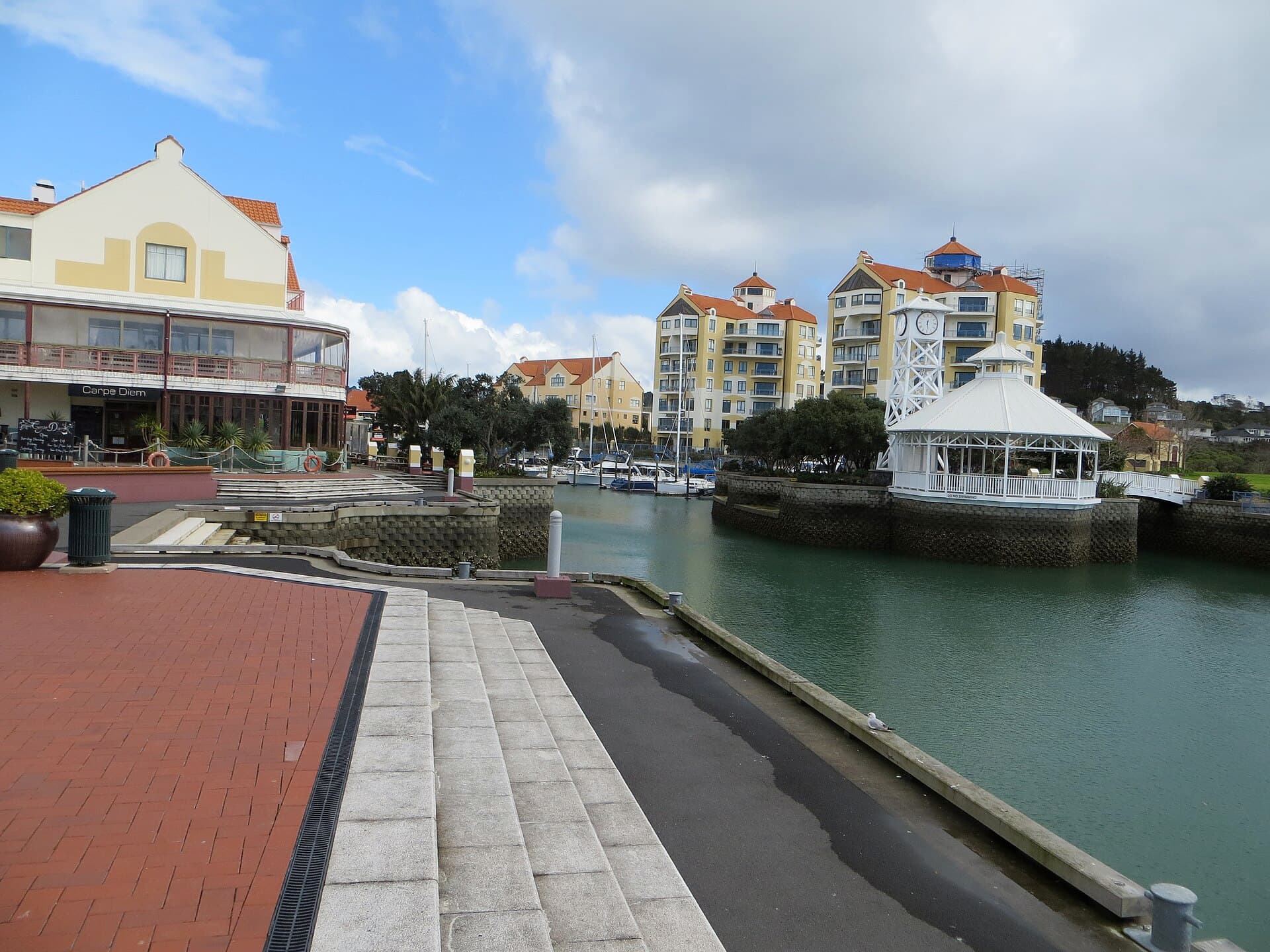 Waterside buildings and a white clock pavilion at the head of Gulf Harbour.
