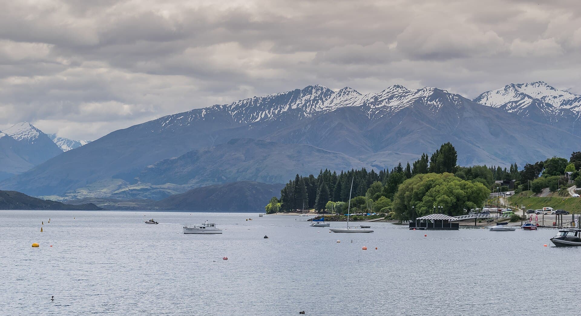 Boats on Lake Wanaka beside the town waterfront, with snow-dusted mountains behind.
