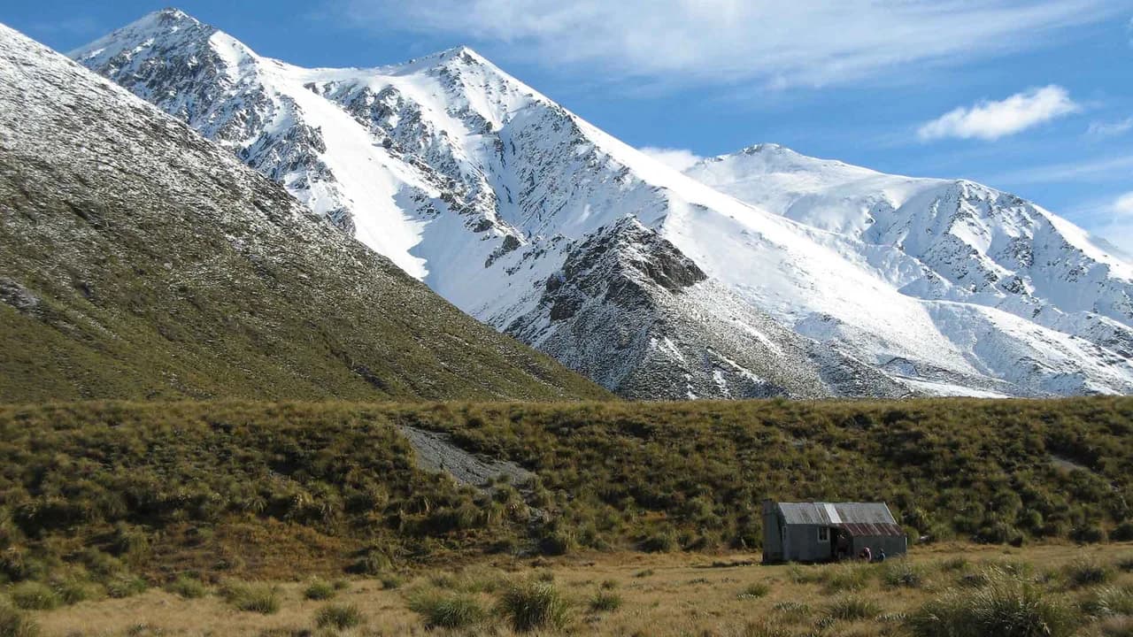 Potts Hut: Potts Hut below snow-covered mountain slopes.