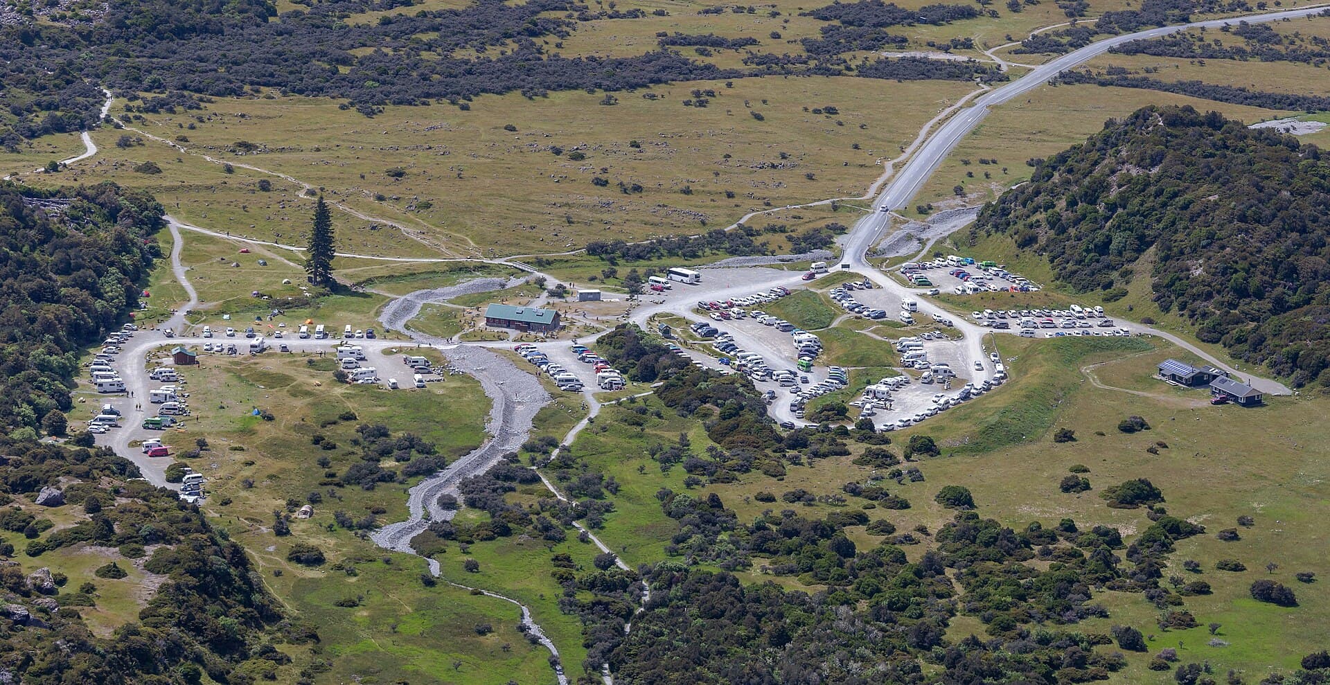 Elevated view of tents and campervans at White Horse Hill, beside the larger car park and valley road.