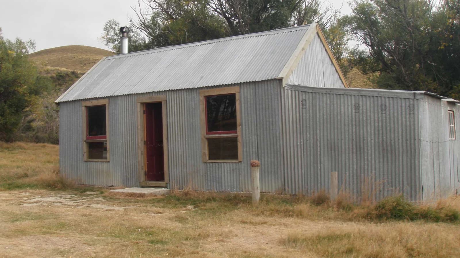 Corrugated-metal building with a chimney and open doorway at Homestead Campsite.